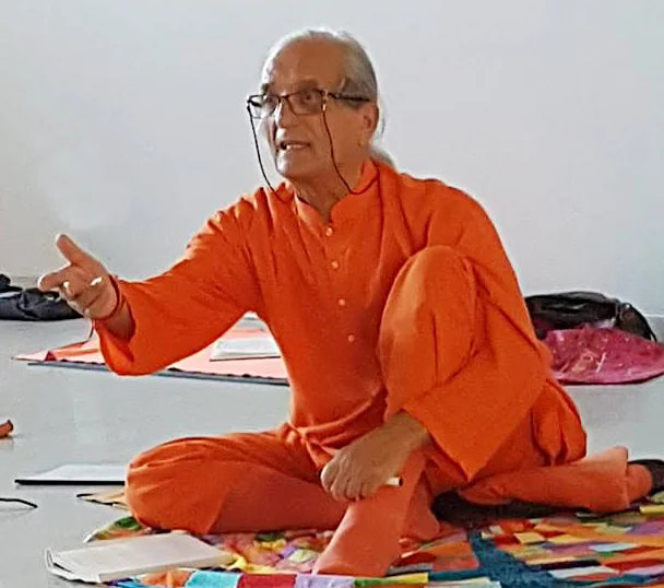 Amadio Bianchi seated on a mat while teaching yoga.